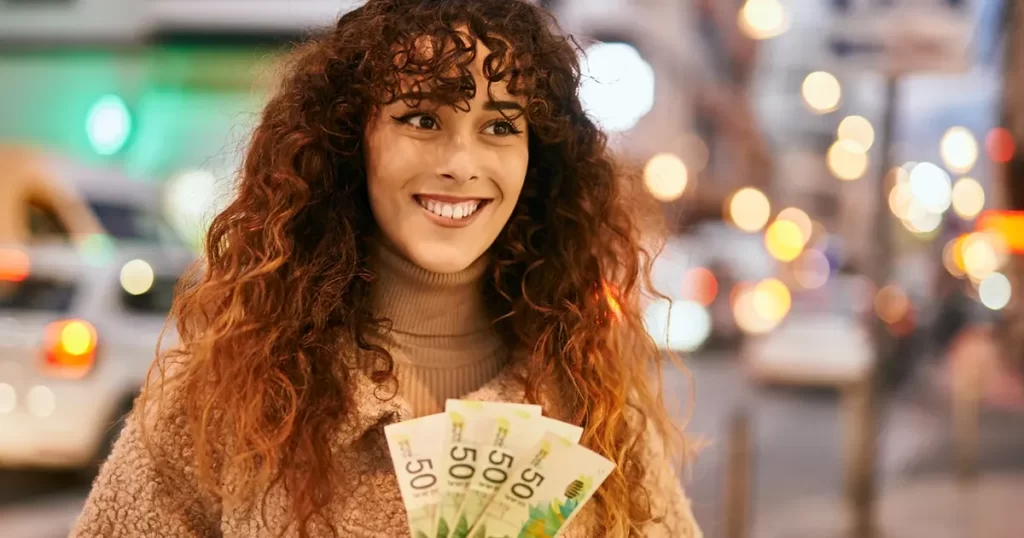 Moça sorrindo segurando notas de dinheiro